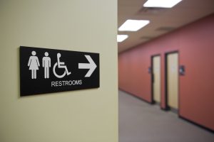 restroom sign pointing down a hall