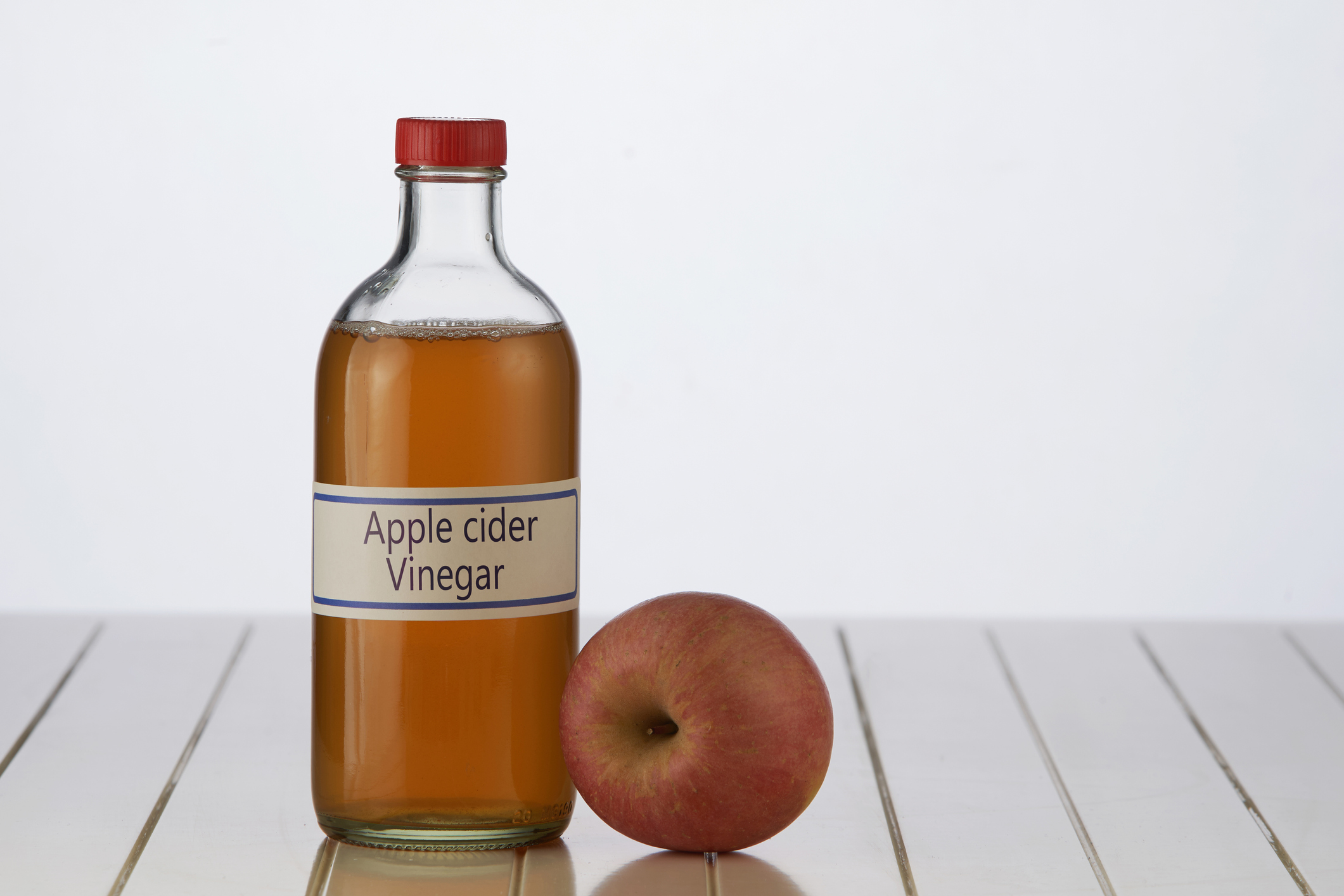 apple cider vinegar bottle beside an apple
